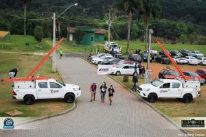 foto de corredores passando entre duas camionetes da cocel com a bandeira da companhia ao meio